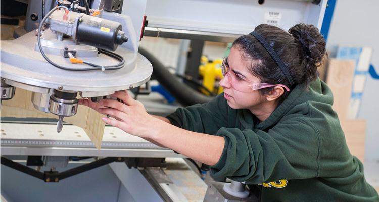female student adjusting saw in wood shop