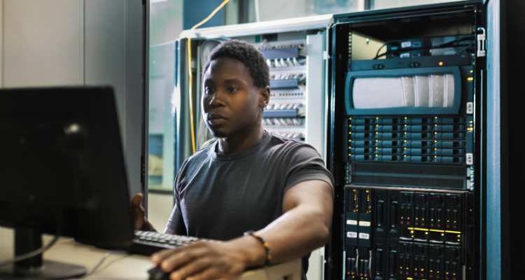 male standing at computer in data center