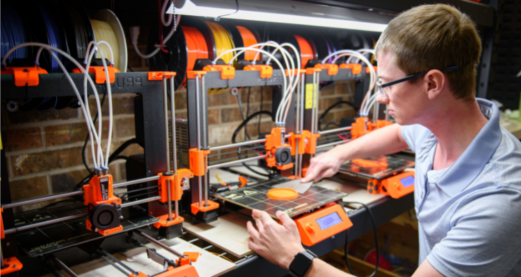 male student working with a commercial 3D printer