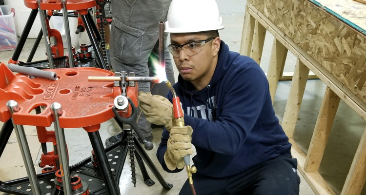 plumbing student sweating pipe fittings together