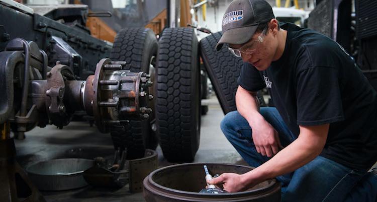 Male working on a large truck tire in garage