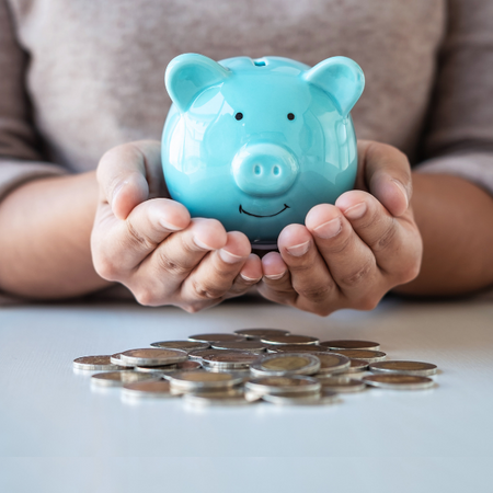 female holding a blue piggy bank in hands