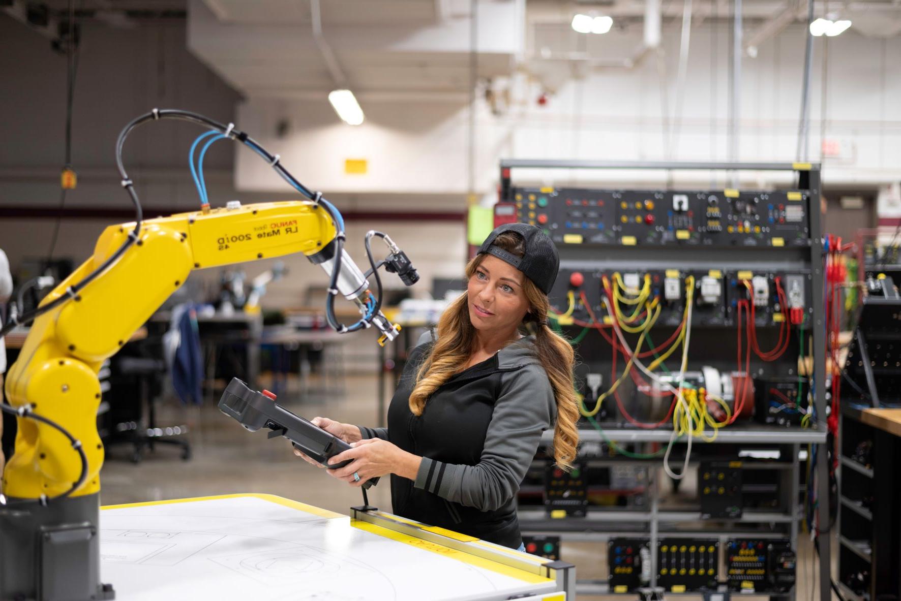 Female robotics student working with remote control and robotic arm