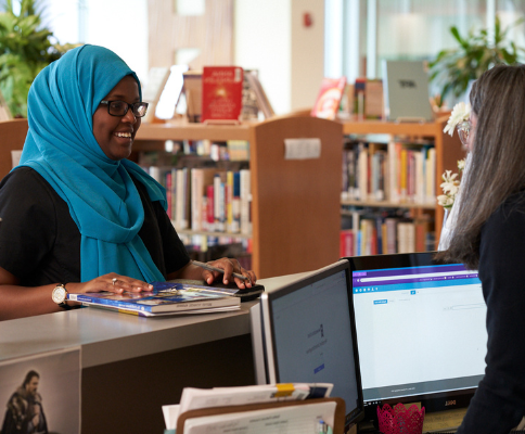 student in library checking out material